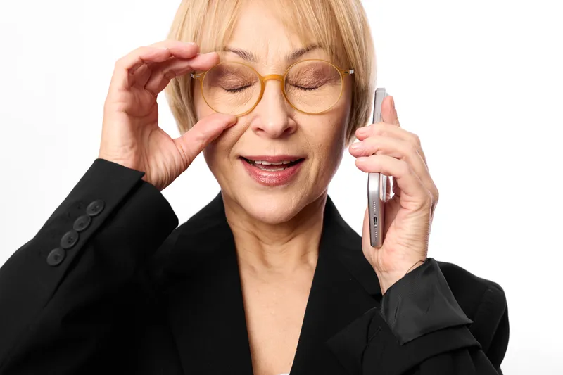 Elderly woman, glasses, phone, communication, business, professional smile, portrait in close up, adjusting hair, talking on mobile, calm, white background.