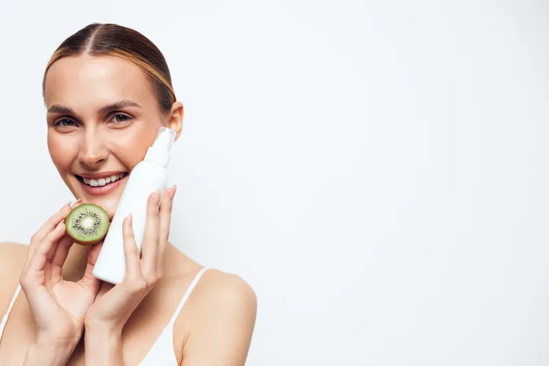 Woman skincare face cream smiling selfcare wellness closeup cucumber hygiene, applies moisturizer with foam on a clean white background, soft lighting spa routine