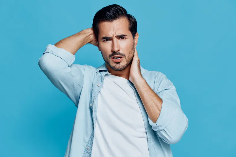 Handsome man looking directly at the camera, showing a thoughtful expression while posing against a solid blue background. Concept: modern lifestyle.