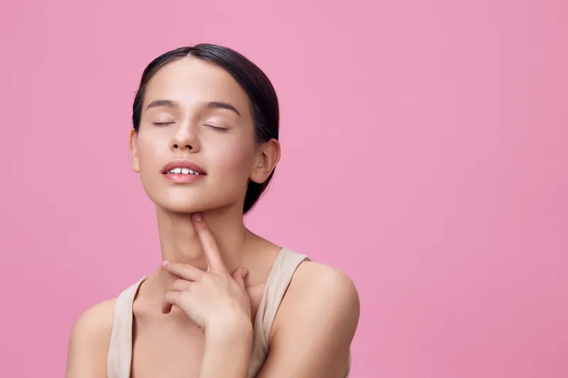 Serene young model with closed eyes on a pink background, conveying calm and peaceful emotions in minimalist fashion, focusing on self care and beauty