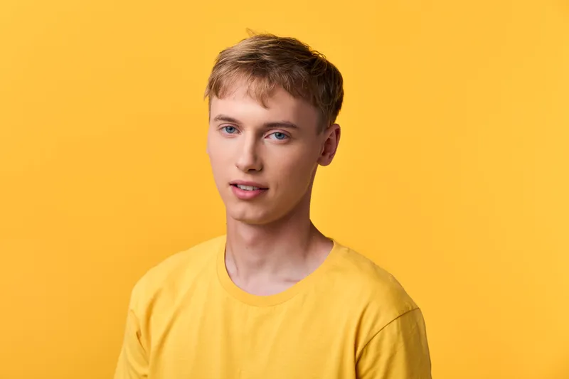 Young man in a bright yellow shirt against a vivid yellow background, casual pose, soft lighting, contemporary fashion, clean studio vibe for marketing and lifestyle campaigns