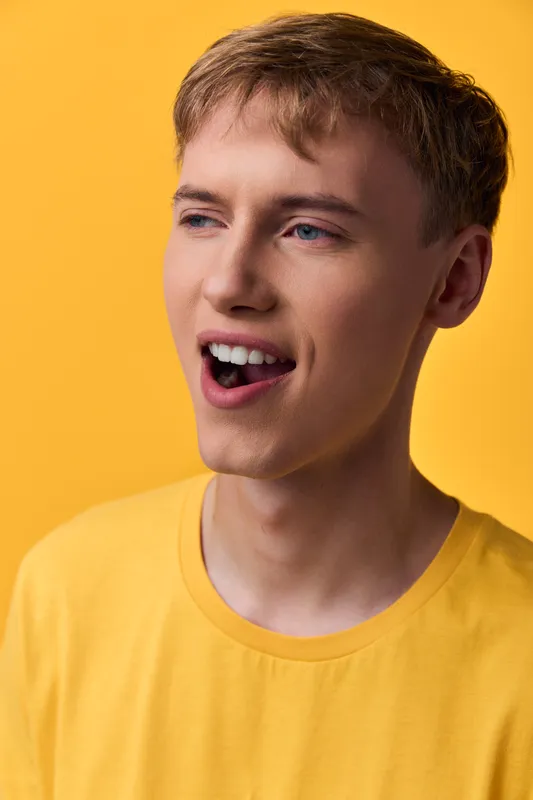 Cheerful man in a yellow shirt smiles against a bright yellow background, casual studio shot capturing warmth, energy and positive mood