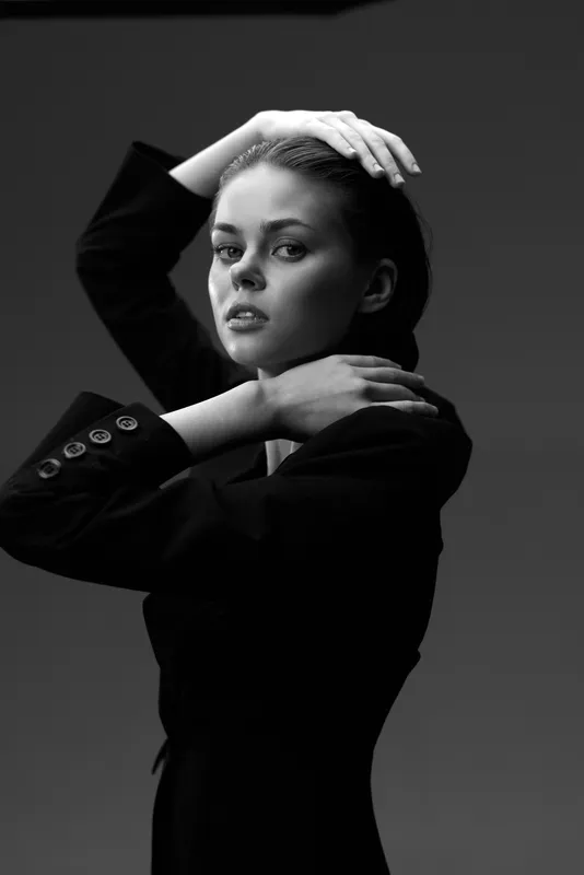 Black and white portrait of a serious woman in a dark jacket with a dramatic pose and intense expression