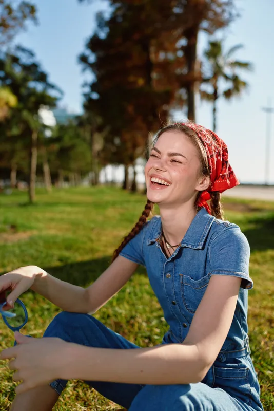 smiling woman dressed in modern boho-western denim street style enjoying sunshine outdoors with film color effect creating warm and vibrant lifestyle mood