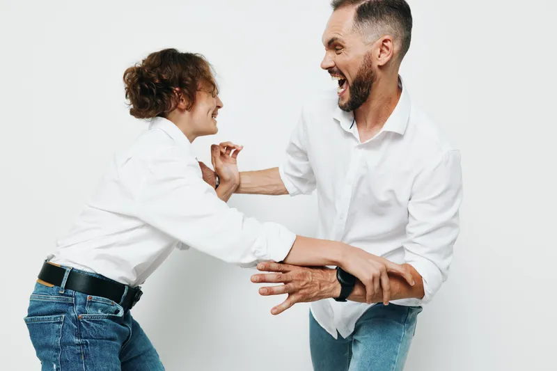 A professional man faces off with a colleague on a bright isolated colored background, capturing energy, confidence, and friendly tension in a business setting.
