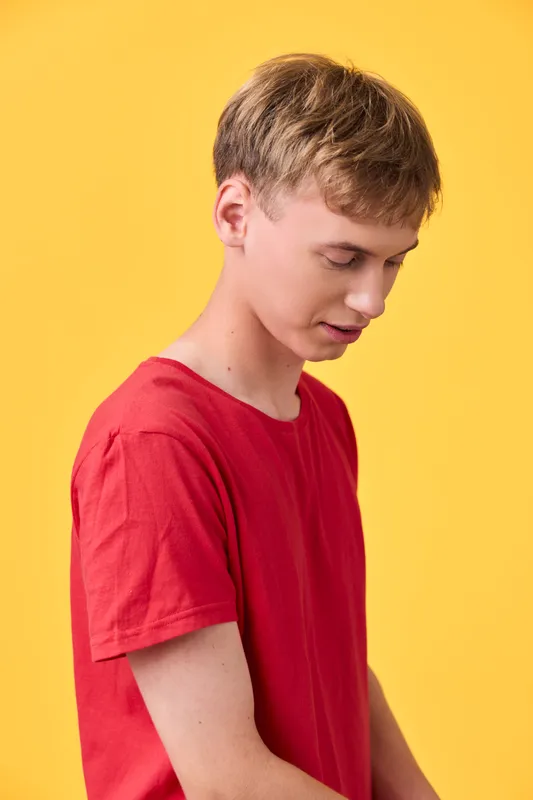 Boy, youth, red shirt, yellow background, side profile, cheerful, casual, child, apparel, fashion in a bright studio conveys simple mood and youthful energy with clean lines and soft lighting