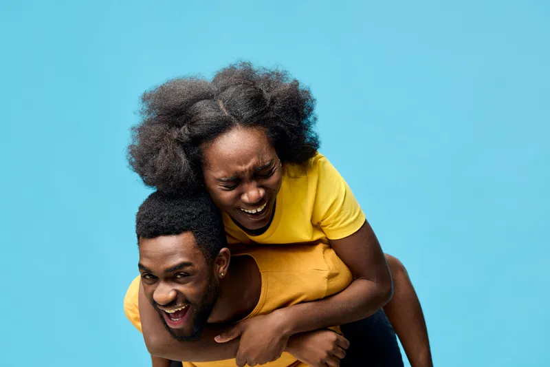 Joyful couple having fun on a blue background, showcasing happy emotions, playful expressions, and vibrant clothing in a seasonal, cheerful setting