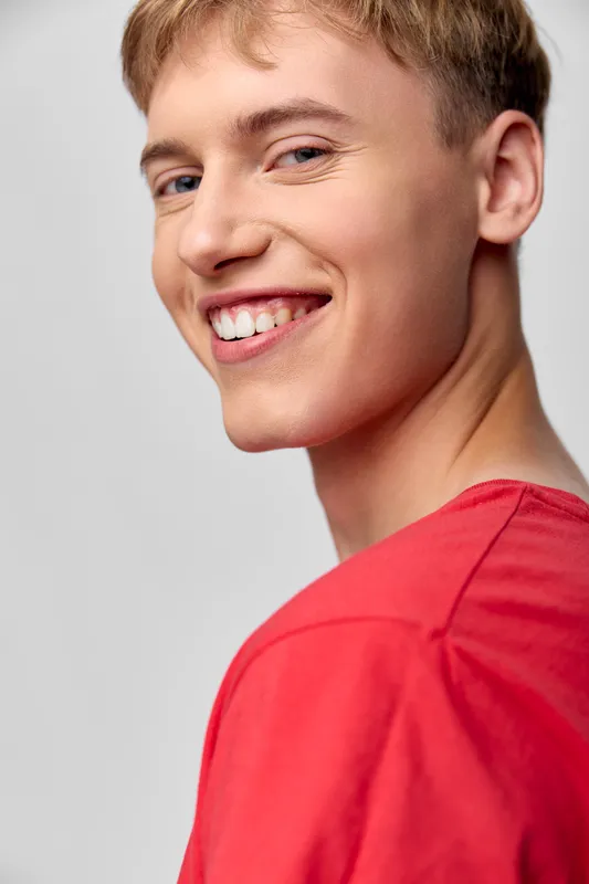 Smile, man, closeup, face with a bright expression wearing a red shirt for lifestyle, fashion, or positive emotion in marketing and stock photography.