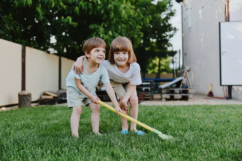 Happy children playing outdoors in a sunny garden, enjoying their time together and exploring nature in a playful atmosphere filled with joy.