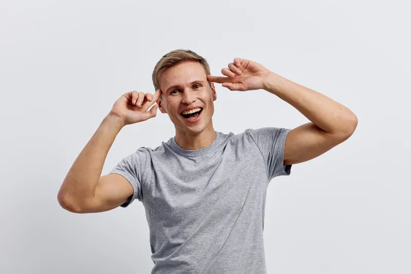 Cheerful smiling man with light brown hair wearing casual gray t-shirt looking directly at camera isolated on plain white background studio portrait. People lifestyle concept