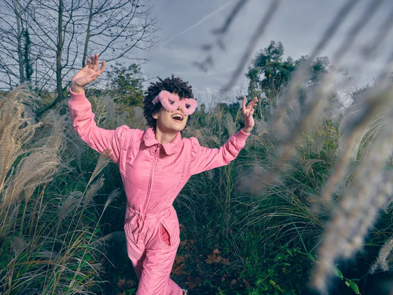 Playful child outdoor pink mask grass imagination nature movement sunshine, exploration and wonder in a carefree moment captured in a sunny natural setting outdoors