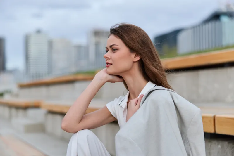 Business woman in a modern urban setting, showcasing confidence and elegance while dressed in stylish attire, against a backdrop of city skyscrapers.