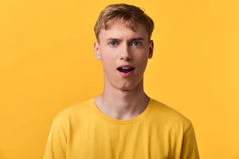 Surprised, astonished man in a yellow shirt against a matching yellow backdrop, showcasing a candid moment of curiosity and reaction, studio setting, facial expression captures surprise and wonder,