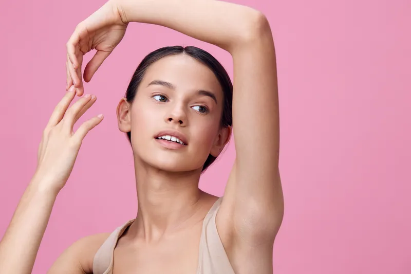 Young woman with natural beauty, posing gracefully against a pink background, showcasing elegance and confidence in a minimalist style