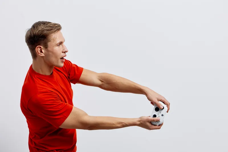 surprised young caucasian man red t-shirt playing video game holding gamepad digital entertainment fun technology concept