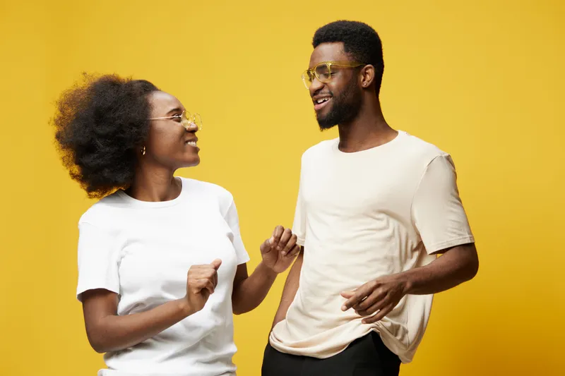 Happy young couple enjoying a joyful moment together against a vibrant yellow background in casual clothing, representing love and connection
