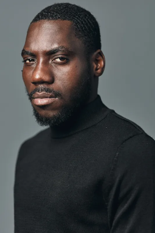 Portrait of African American man with dark skin wearing black turtleneck in creative visual designer style. Serious expression, studio lighting and neutral background for professional look.