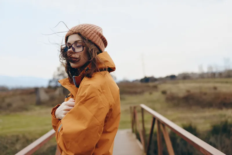 Woman mother child outdoors lifestyle autumn walking in countryside, warm coat and hat, glasses, wind on a bridge path, cozy daylight mood, family portrait, soft focus
