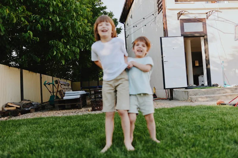 Happy children playing outdoors in a sunny backyard, enjoying summer joy and carefree moments together with laughter and fun.