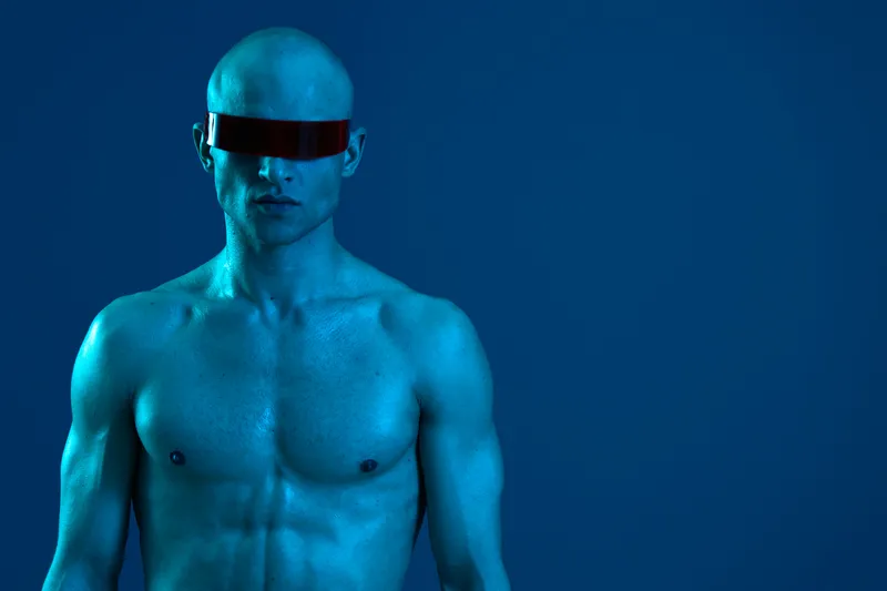 Futuristic man with sunglasses in a striking blue light, showcasing a unique and modern aesthetic that captures attention and evokes intrigue.