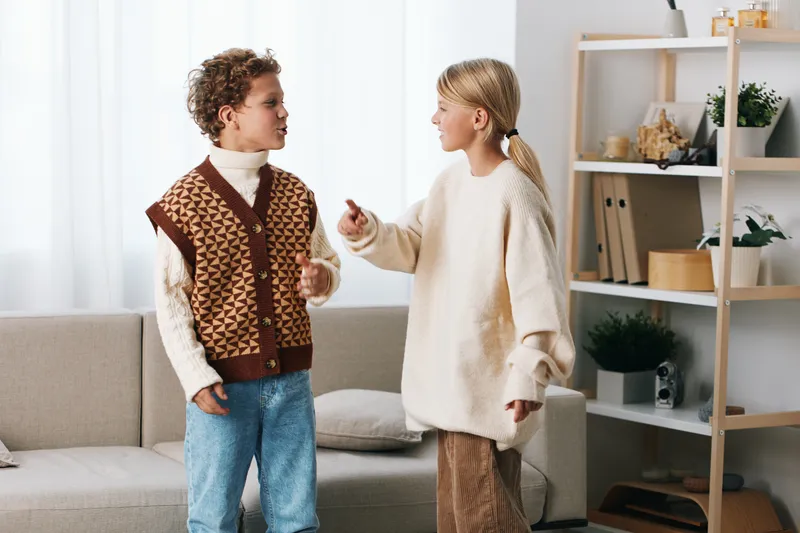 Authentic lifestyle scene featuring children at play with a school theme, capturing candid interaction, warm wardrobe, and a cozy home setting that conveys genuine learning energy.