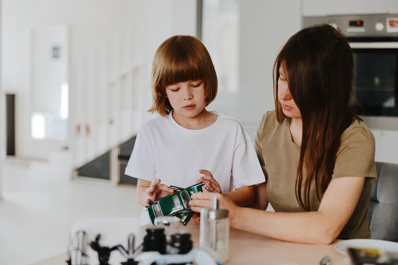 Caring woman teaching child to be responsible with money, enjoying quality time in a modern kitchen setting. A warm, educational moment that fosters learning together.