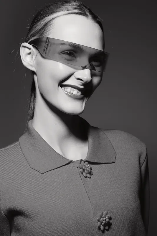 Young caucasian woman with fair skin wearing stylish transparent sunglasses smiles confidently in black and white portrait. Concept of fashion, beauty, and modern eyewear.