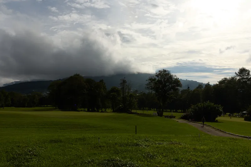 Serene Golf Course Landscape Under Cloudy Sky with Lush Greenery and Hills