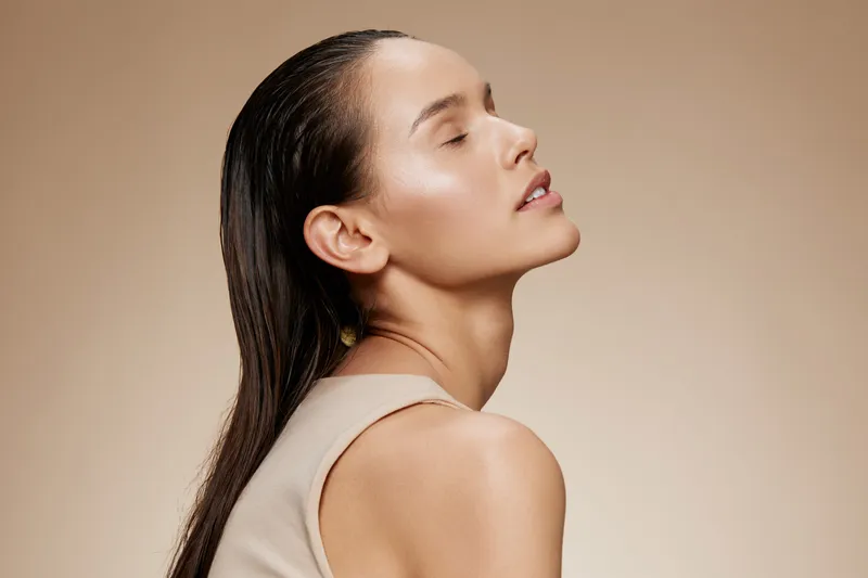Serene woman with long hair and closed eyes, showcasing natural beauty and healthy skin, with a neutral beige background and soft lighting, ideal for wellness themes