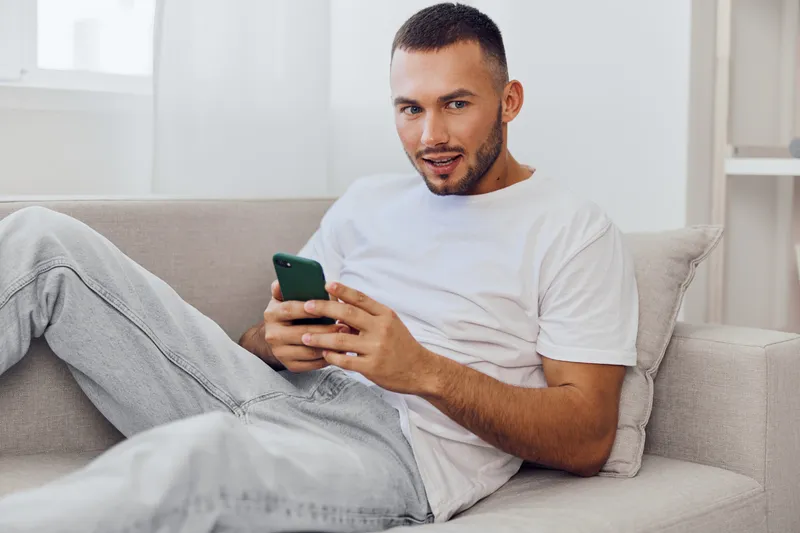 Relaxed man enjoying a digital detox while scrolling on his phone, representing the balance between technology and mental health in modern life.