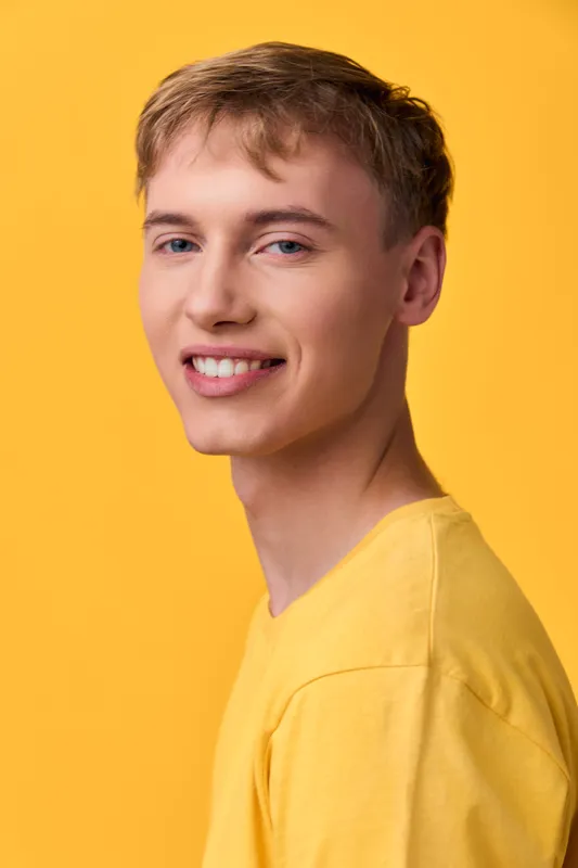 Young man smiling in a yellow shirt against a vivid yellow background studio setup, a casual headshot perfect for fashion lifestyle and branding visuals