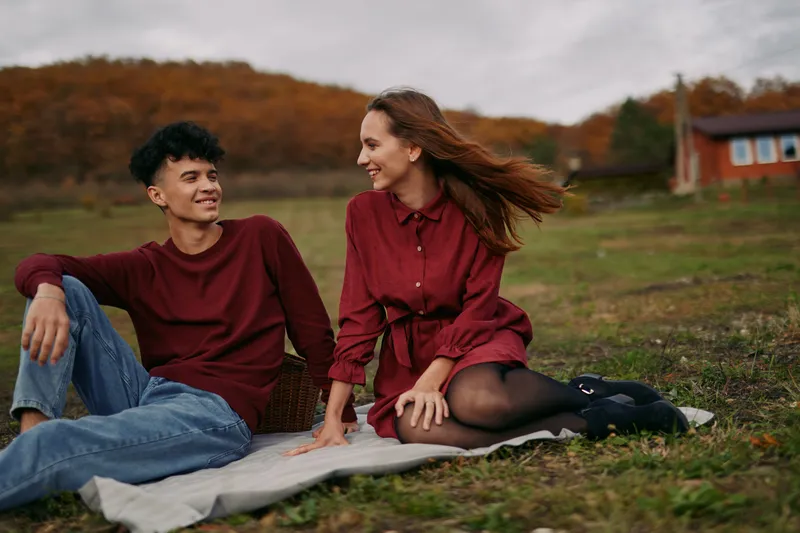 Authentic moment of connection between two friends in a field, candid laughter and natural pose, a scene that conveys trust, comfort, and genuine companionship.