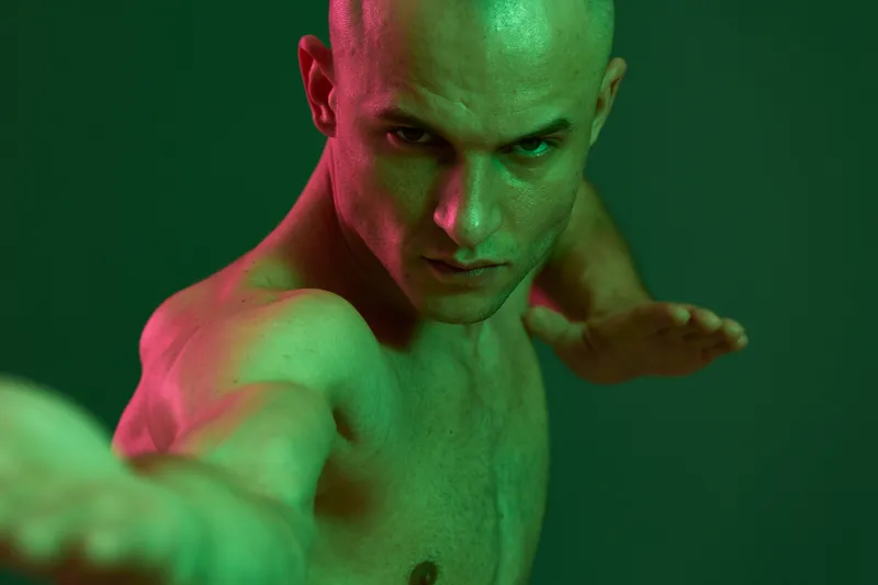 Athletic man posing dramatically with a strong expression. The vibrant green and subtle red hues create a striking contrast in this energetic composition.