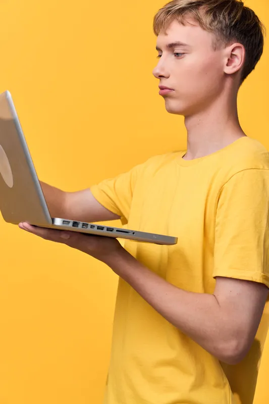 Laptop, young man, technology, learning, computer and screen on a bright yellow background, capturing focus, study and digital exploration in a modern casual setting