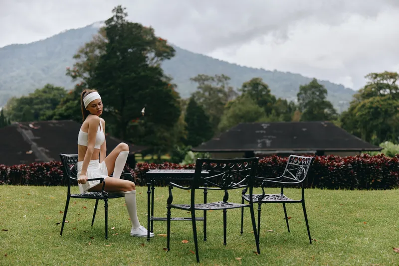 Stylish model poses in a modern outdoor setting, showcasing fashion and elegance amidst nature, with a focus on athletic wear and a serene mountain backdrop