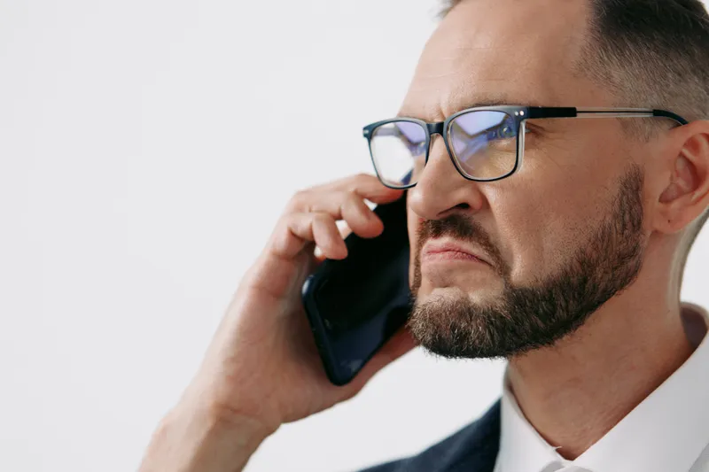 A focused business professional on an isolated colored background, conveying confident mood and thoughtful emotion while speaking on a mobile phone during a key call.