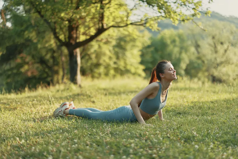 Fit young woman practicing yoga outdoors in a serene green park, showcasing healthy lifestyle, mindfulness, and inner peace during a sunny day