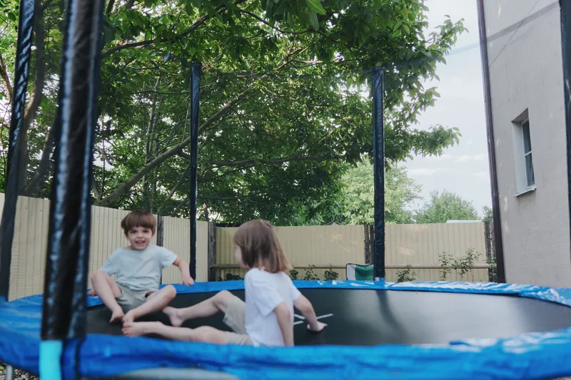 Happy children jumping on a trampoline in a sunny garden, enjoying their time together while playing and laughing outdoors, creating joyful memories.