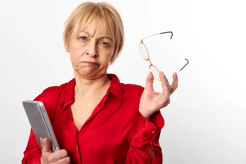 Senior woman holding eyeglasses and glasses frame, worried portrait, eyesight health check with clipboard, studio light, plain white background, concept of optometry and aging care