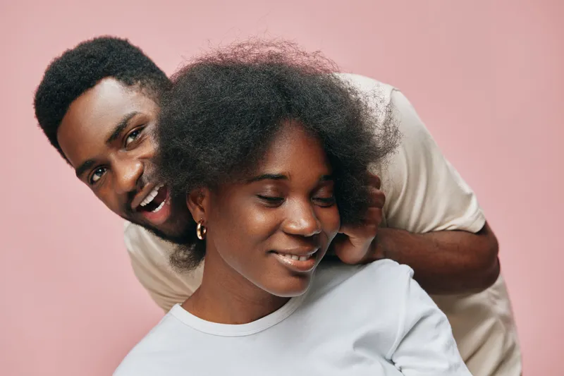 Happy couple with natural hair posing against a pink background, showcasing love, joy, and connection, ideal for relationships and diversity concepts