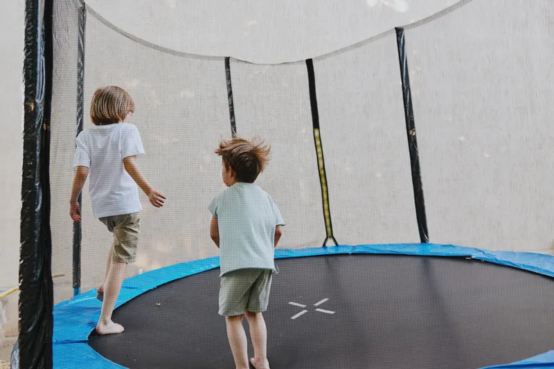 Two joyful children playing on a trampoline, enjoying a fun day outdoors with vibrant colors and laughter in the air. Perfect for summer activities and family joy.