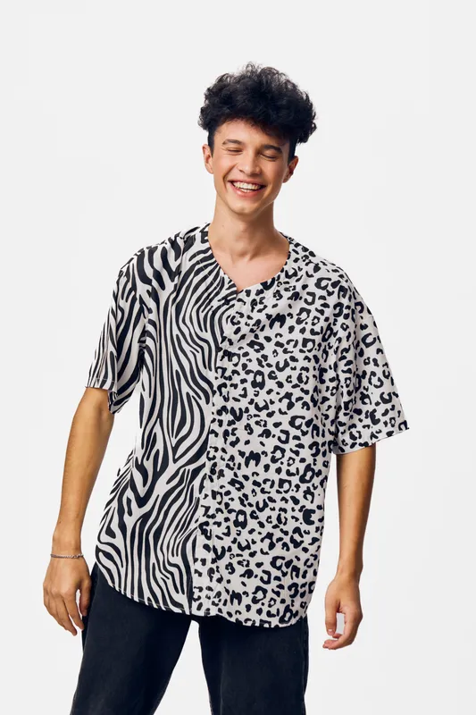 young man wearing a black and white animal print shirt smiling joyfully with eyes closed on a clean white background, casual style, expressive happiness