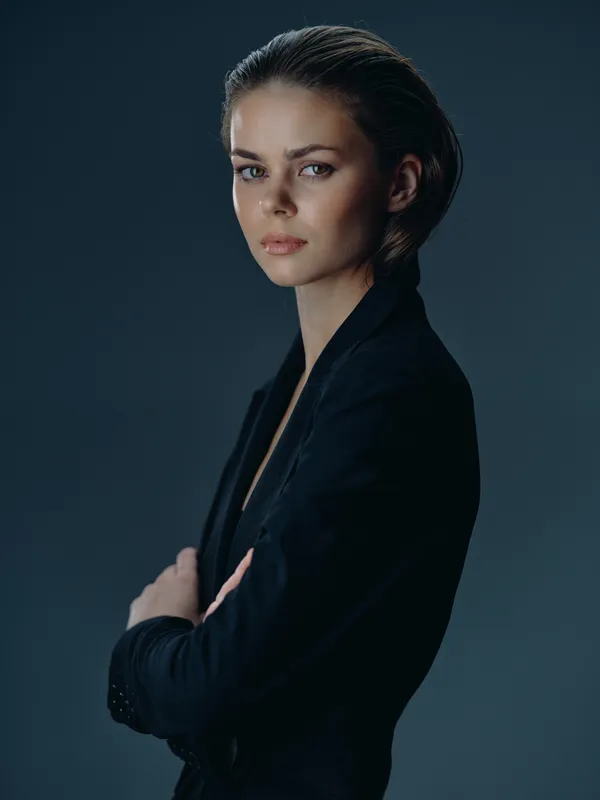 serious woman in black blazer with crossed arms posing indoors calm confident expression