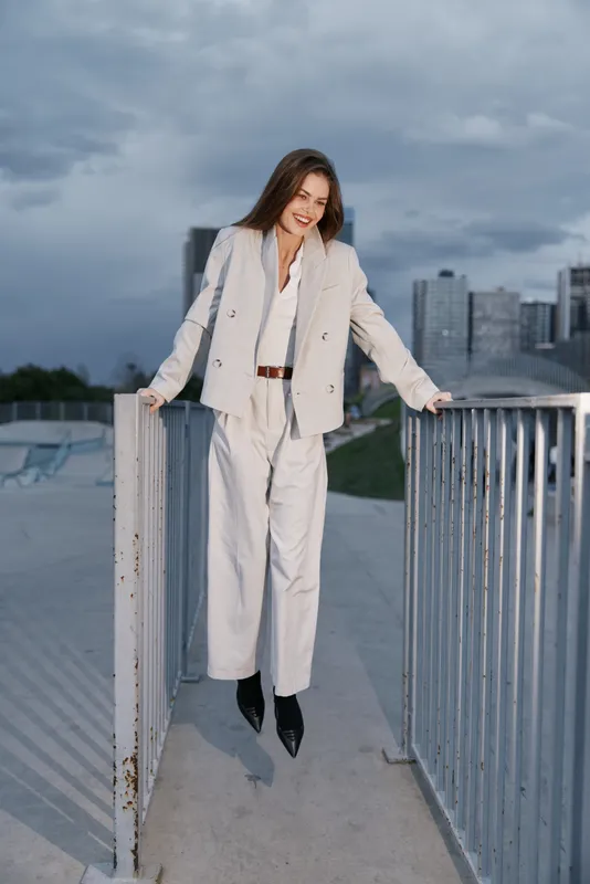 woman in beige suit smiling confidently outdoors urban background business style professional attire autumn sky