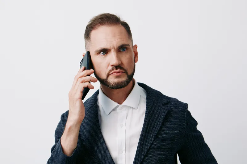 Professional businessman on a call, exuding focus and determination against an isolated colored backdrop. He appears confident, composed, and ready to discuss important matters.