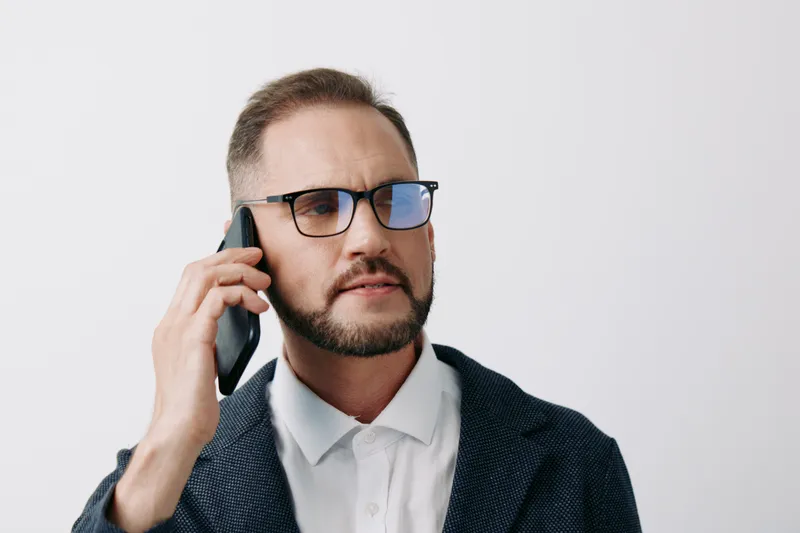 A professional business man on a mobile call stands against an isolated colored backdrop, exuding confidence, focus, and composure in a corporate context.