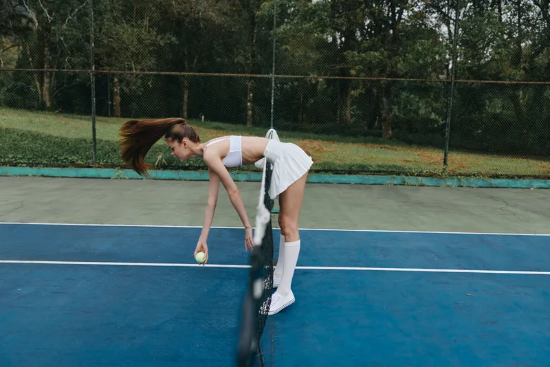 Young female tennis player preparing to serve on a vibrant outdoor court, showcasing determination, athleticism, and summer style