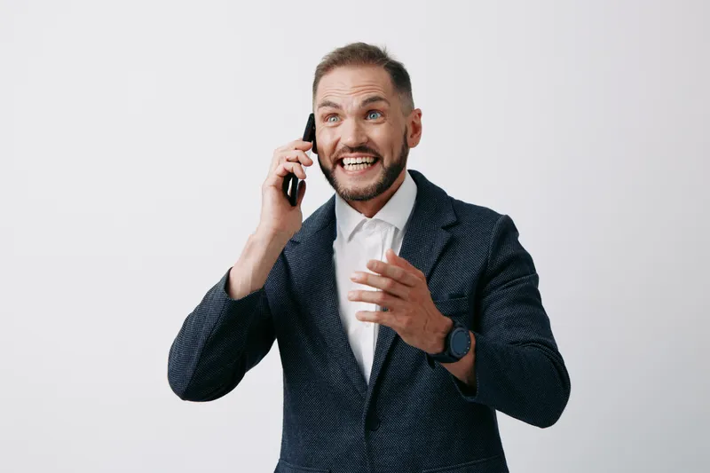 A professional businessman on a colored isolated background speaks on a phone, displaying strong emotion, engagement, and confidence as he communicates an important message.
