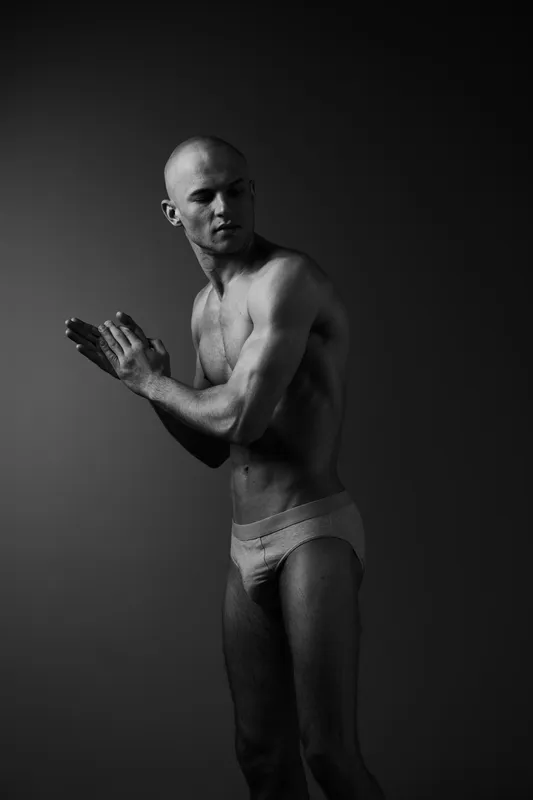 Athletic man preparing for a workout, showcasing toned muscles and determination in black and white. Captivating pose with dramatic lighting highlighting strength.