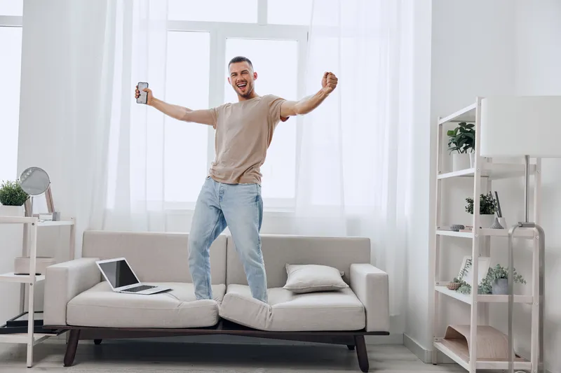 Happy man celebrating a breakthrough during a digital detox at home, balancing work and personal life while embracing emotional minimalism and self-care.